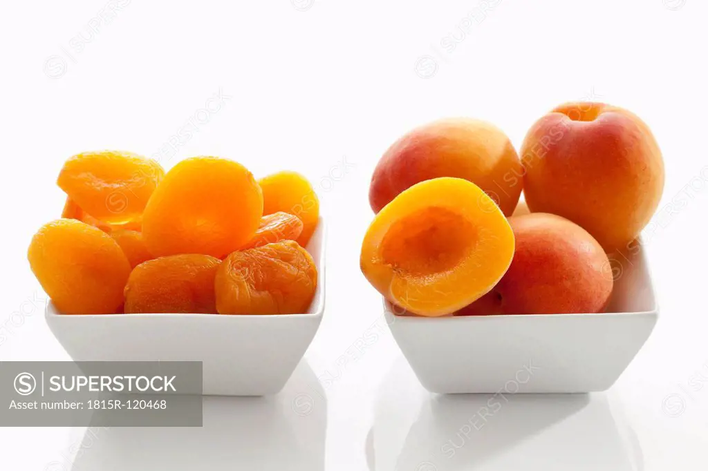 Fresh and dried apricots in bowl on white background, close up