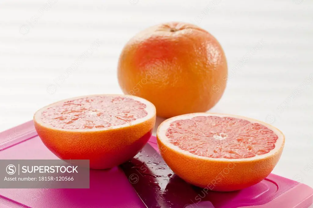 Grapefruit with chopping board and knife, close up