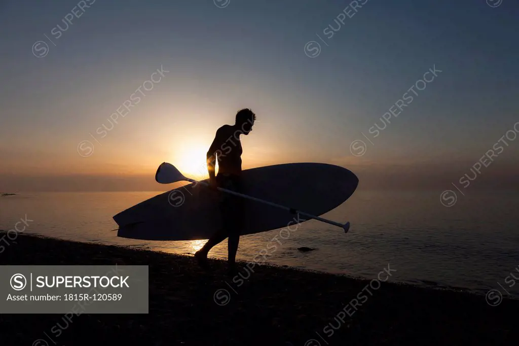Germany, Schleswig Holstein, Man with stand up paddle board at Baltic Sea