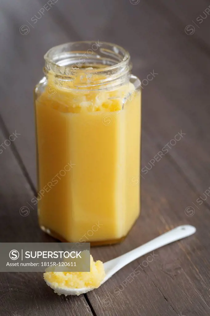 Jar of butter on wooden table, close up