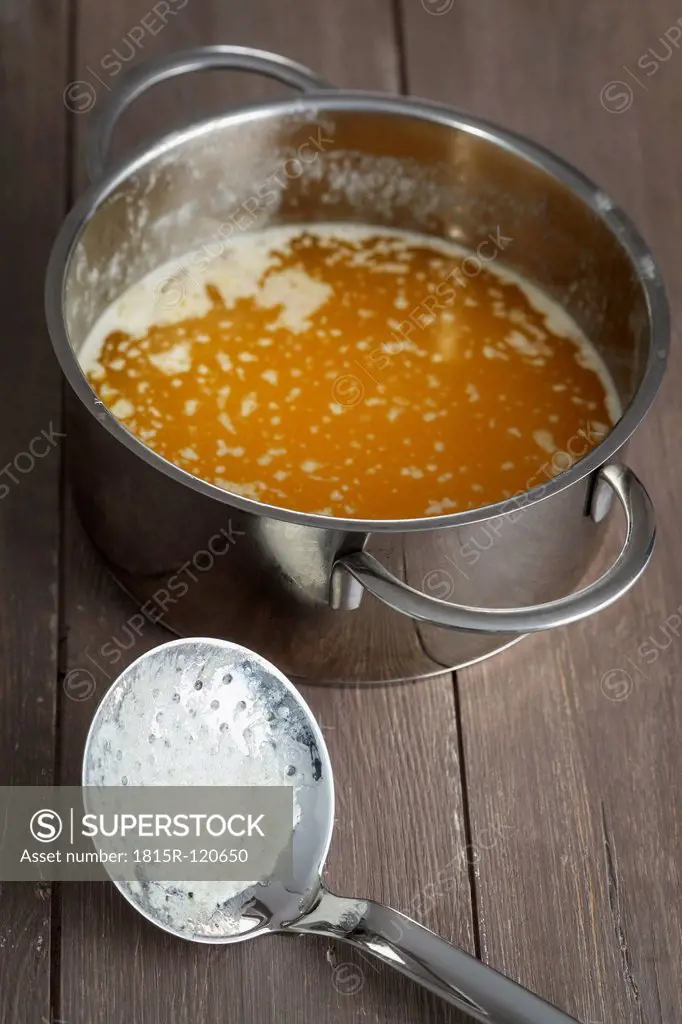 Melted butter in pot beside strainer, close up