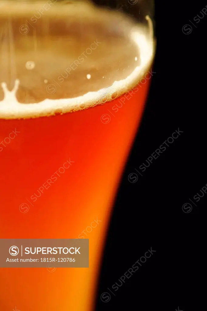 Glass of wheat beer against black background, close up