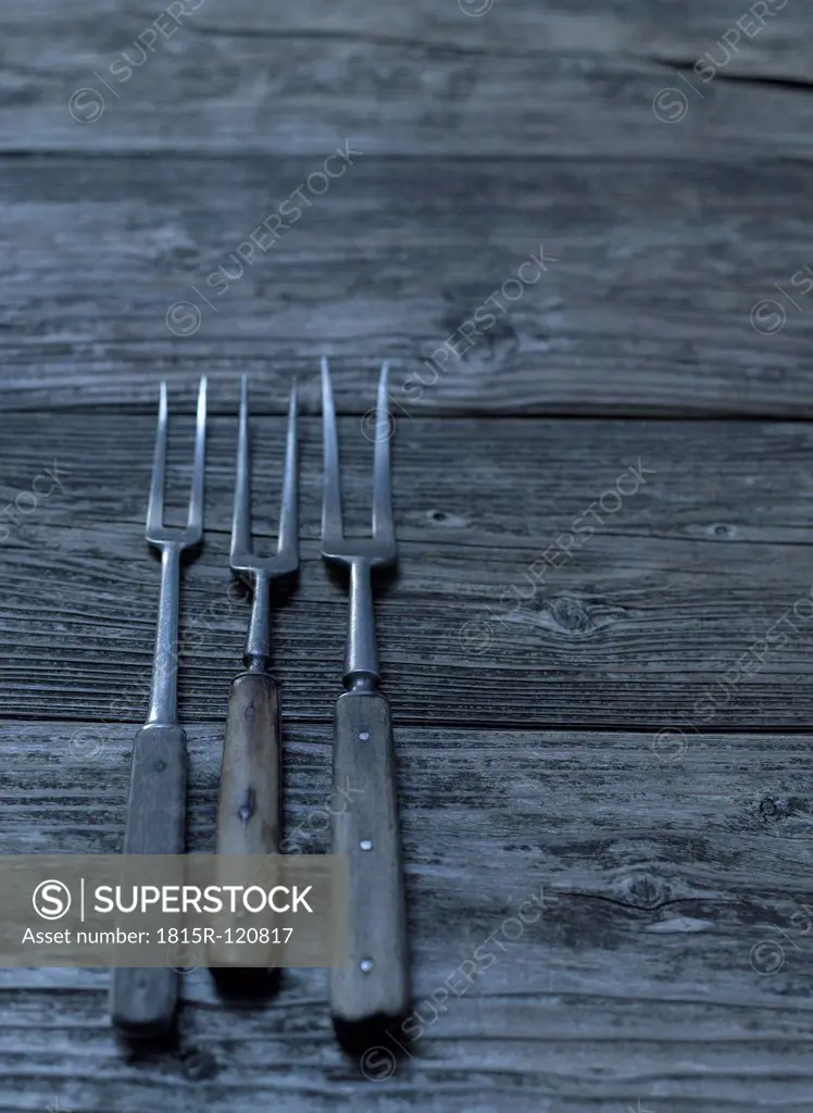 Old fashioned forks on wooden table, close up