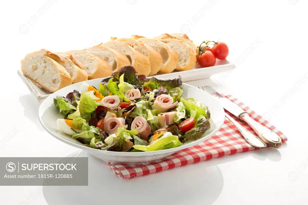 Plate of salad with ham and cheese and bread in tray on white background, close up