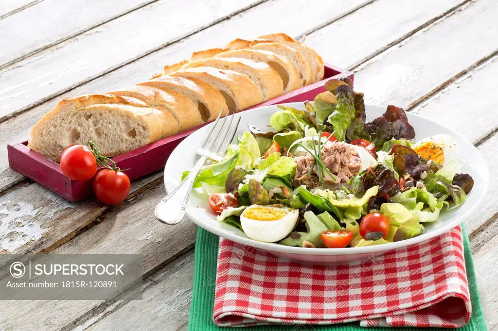 Plate of salad with tuna and bread in tray on table, close up