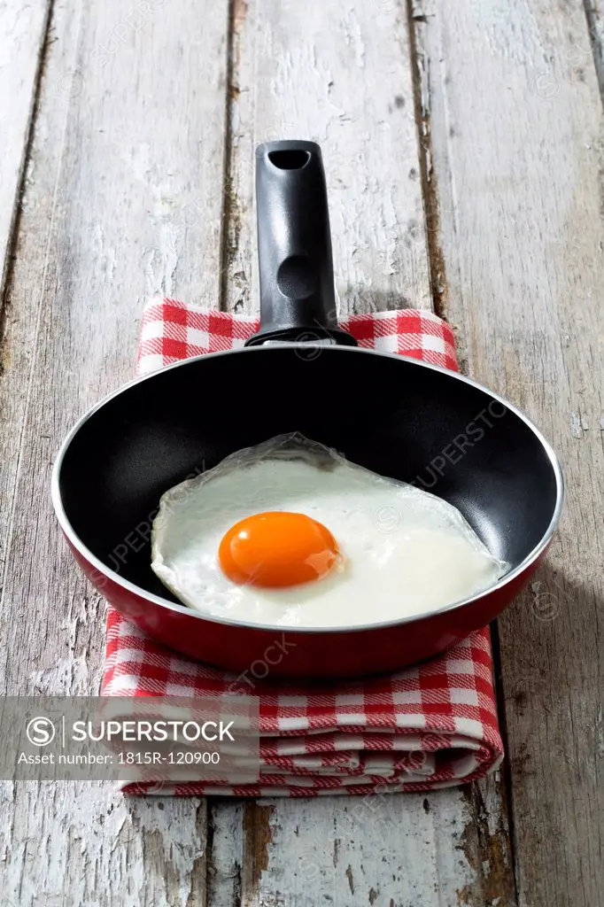 Fried egg in pan on wooden table, close up
