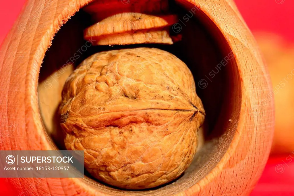 Walnut with nutcracker on red background, close up