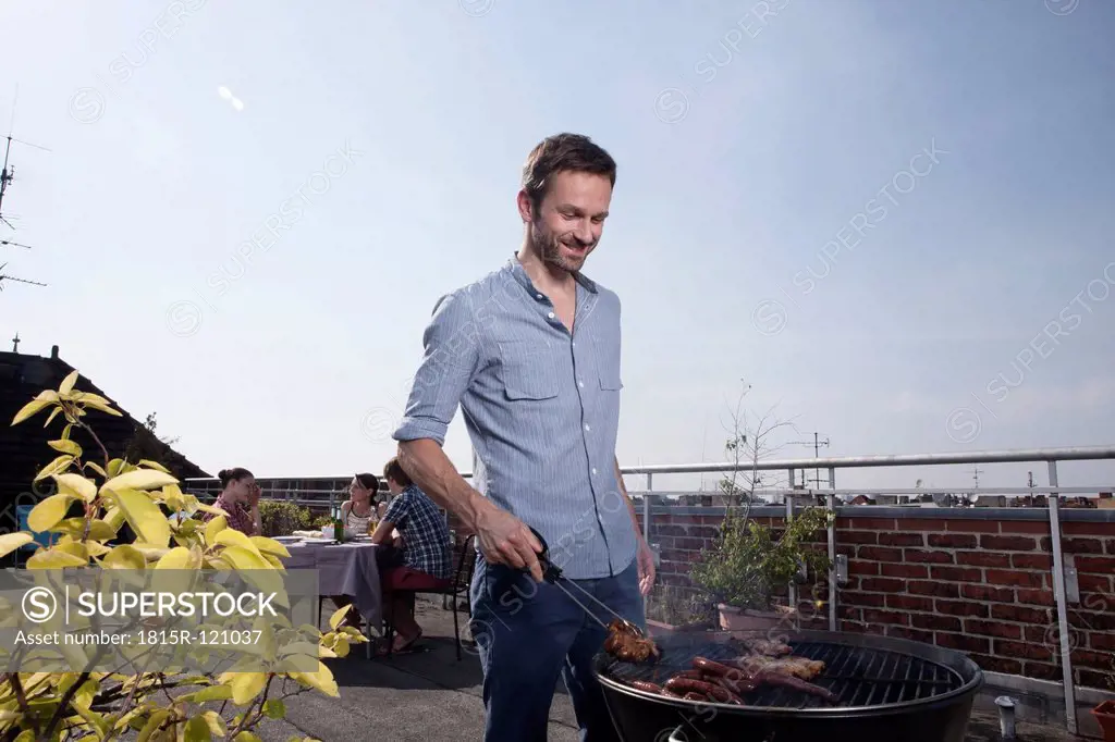 Germany, Berlin, Man barbecueing on grill, smiling