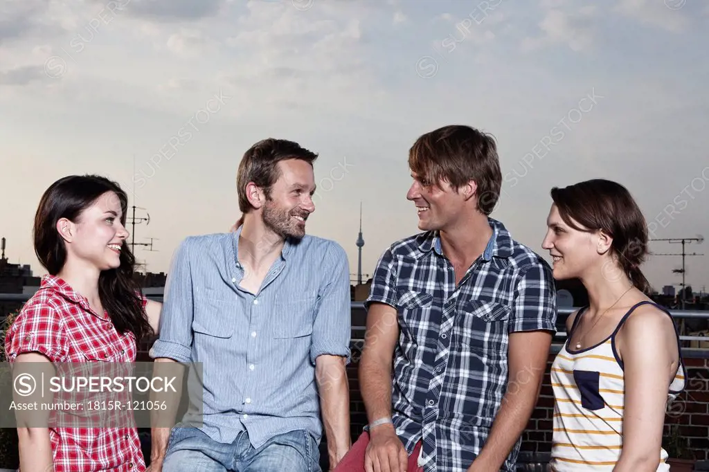 Germany, Berlin, Men and women on roof terrace, smiling