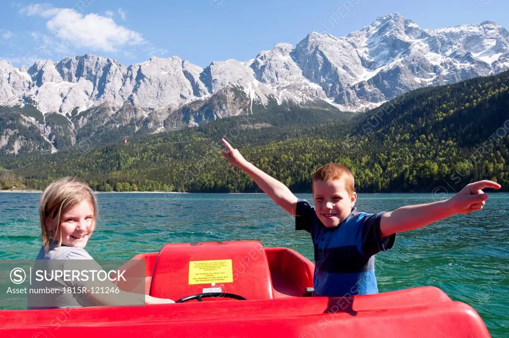 Germany, Bavaria, Boy and girl in paddleboat on Lake Eibsee with Zugspitze and Wetterstein mountains in background