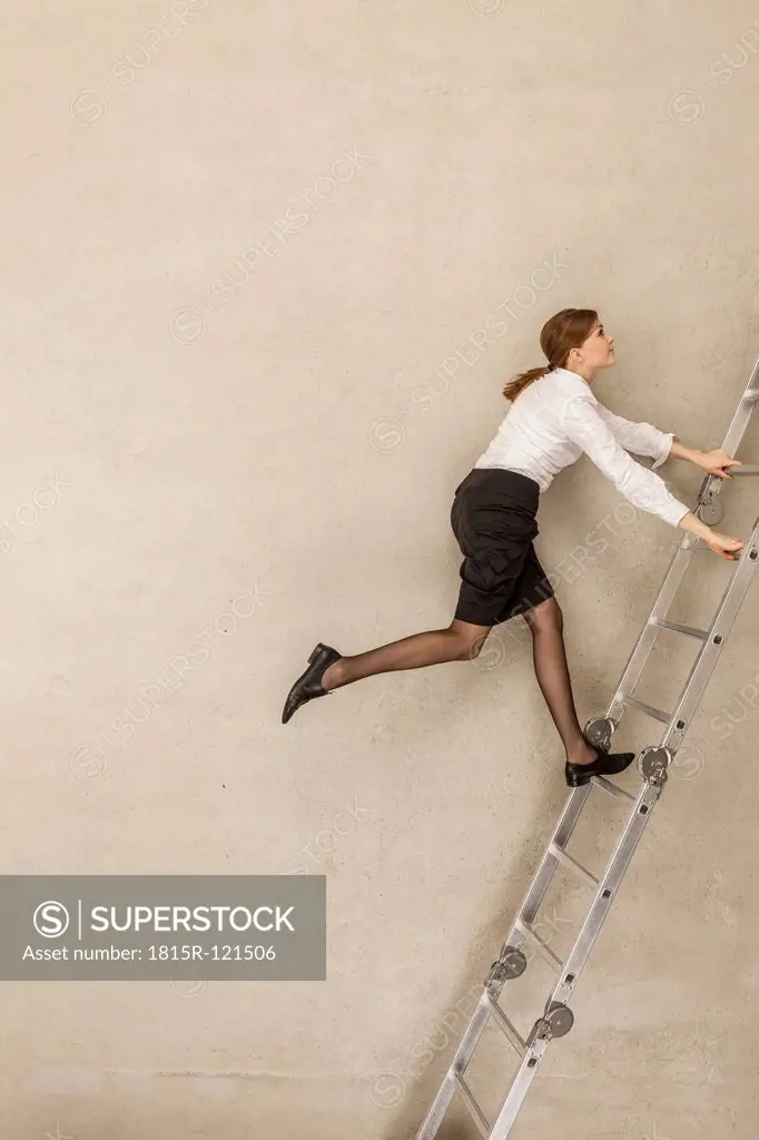 Businesswoman climbing ladder in office