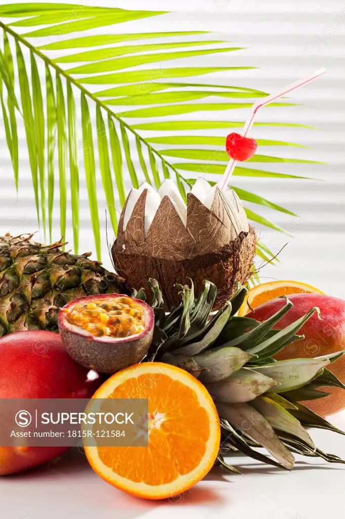 Coconut with drinking straw and fruits, close up