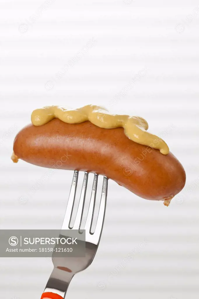 Bockwurst with mustard on fork, close up