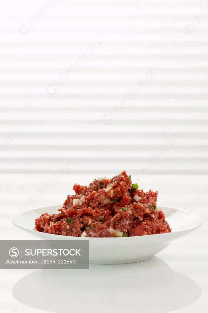 Plate of minced meat with chopped onions and herbs, close up
