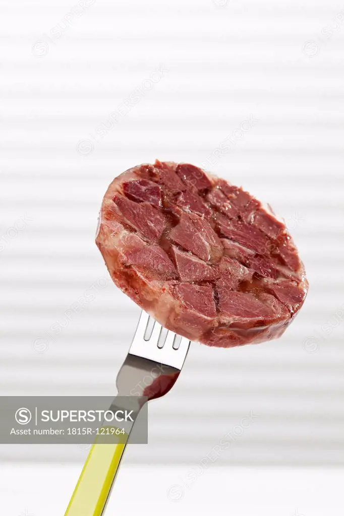 Slice of boar in aspic on fork, close up