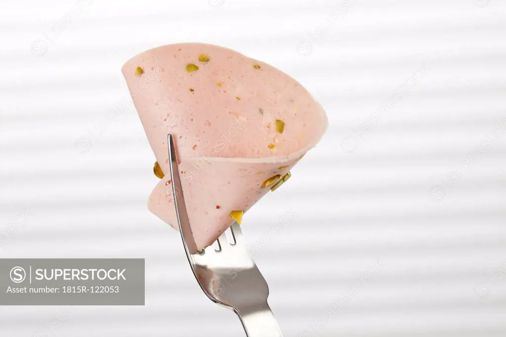 Mortadella sausage with pistachio on fork, close up