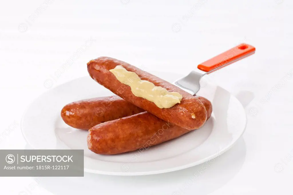Ground pork sausage with mustard on fork, close up