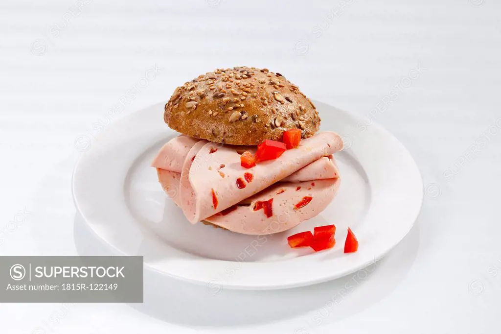 Sandwich of bread roll with mortadella and paprika on plate, close up