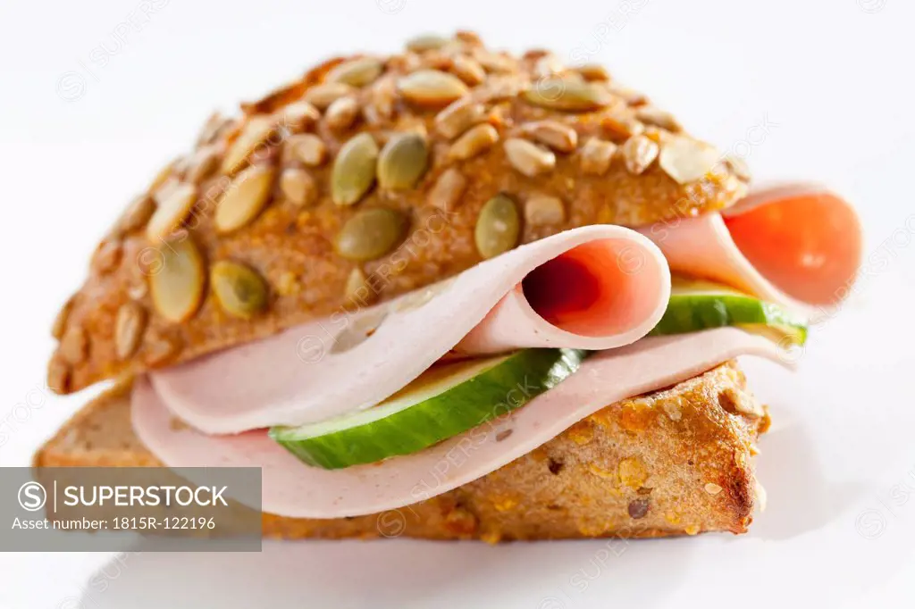 Sandwich of grain bread roll with mortadella and mushrooms on white background, close up