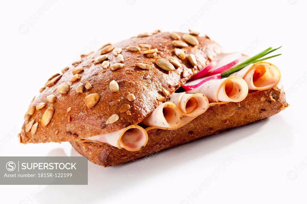Sandwich of grain bread roll with mortadella and poultry on white background, close up