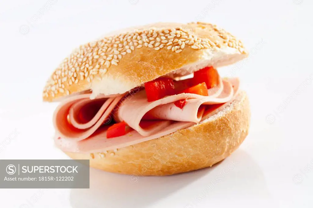 Sandwich of sesame seed bread roll with motadella and paprika on white background, close up