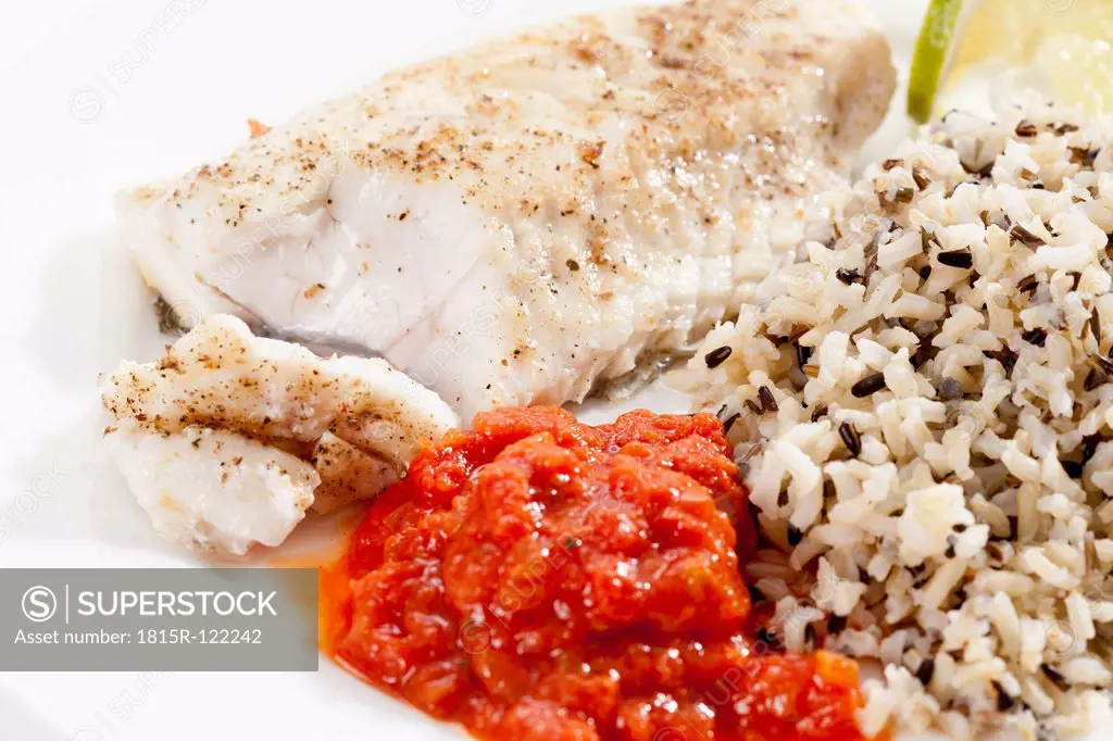 Plate of fried fresh pike with boiled rice and tomato dip, close up