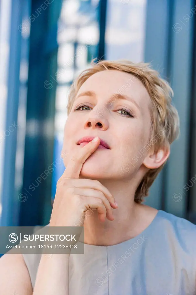 Portrait of blond woman with head back and finger on her mouth