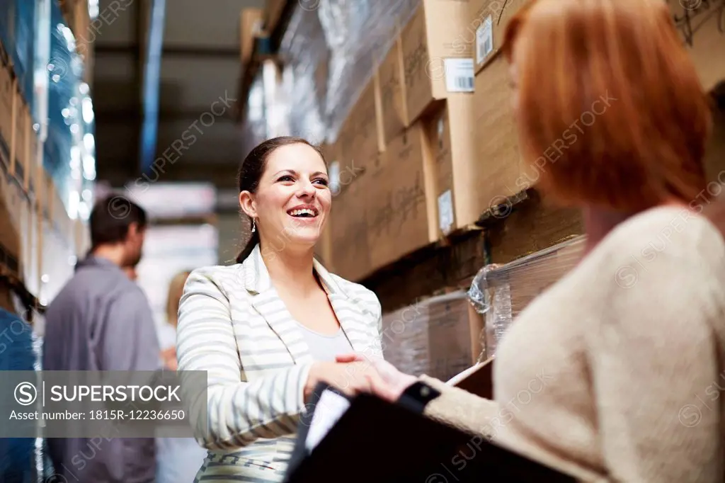 Two women shaking hands in warehouse