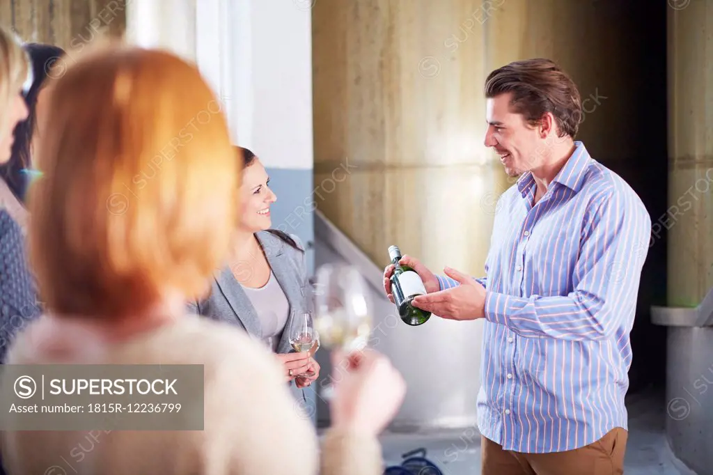 Man presenting bottle of wine on shop floor
