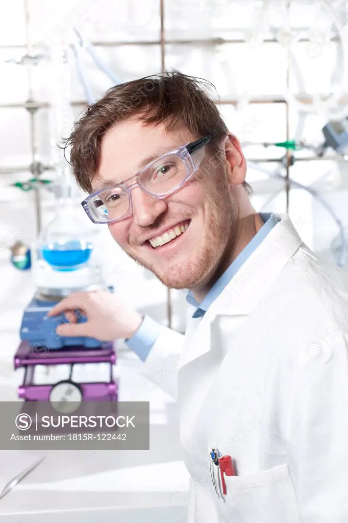 Germany, Portrait of young scientist preparing chemical process, smiling