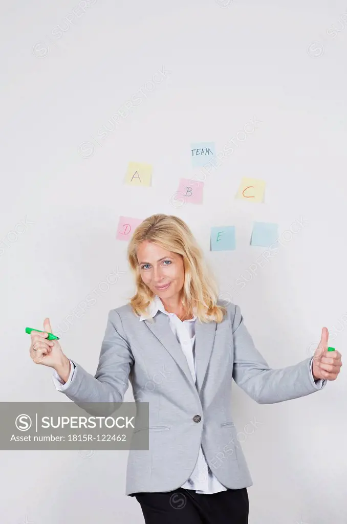 Portrait of businesswoman holding marker, adhesive note in background