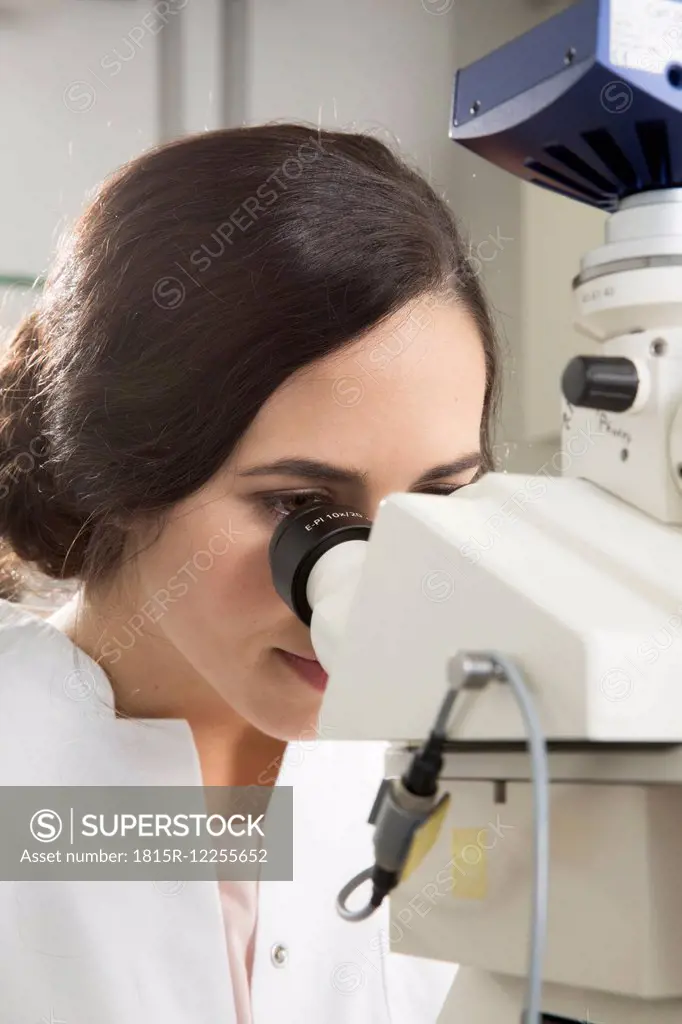 Germany, Berlin, female researcher working in laboratory, microscope
