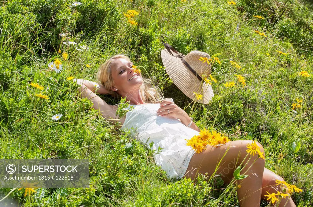 Austria, Altenmarkt-Zauchensee, Mid adult woman lying in alpine meadow with arnica, smiling