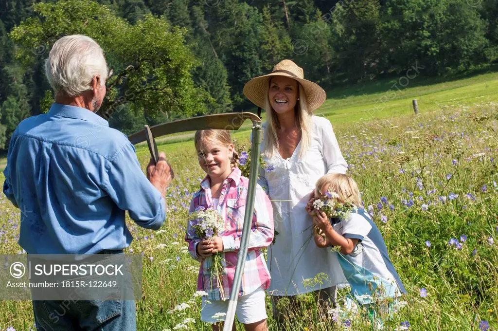 Germany, Salzburg, Farmer and family in summer meadow, smiling