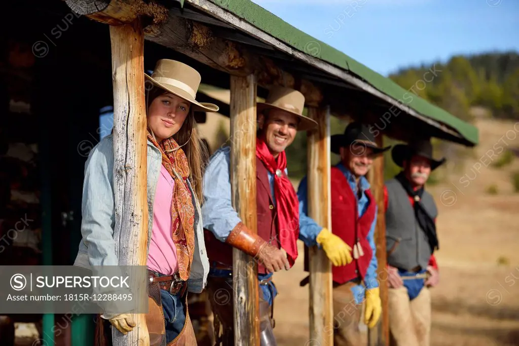 USA, Wyoming, cowgirl and three cowboys standing under a porch