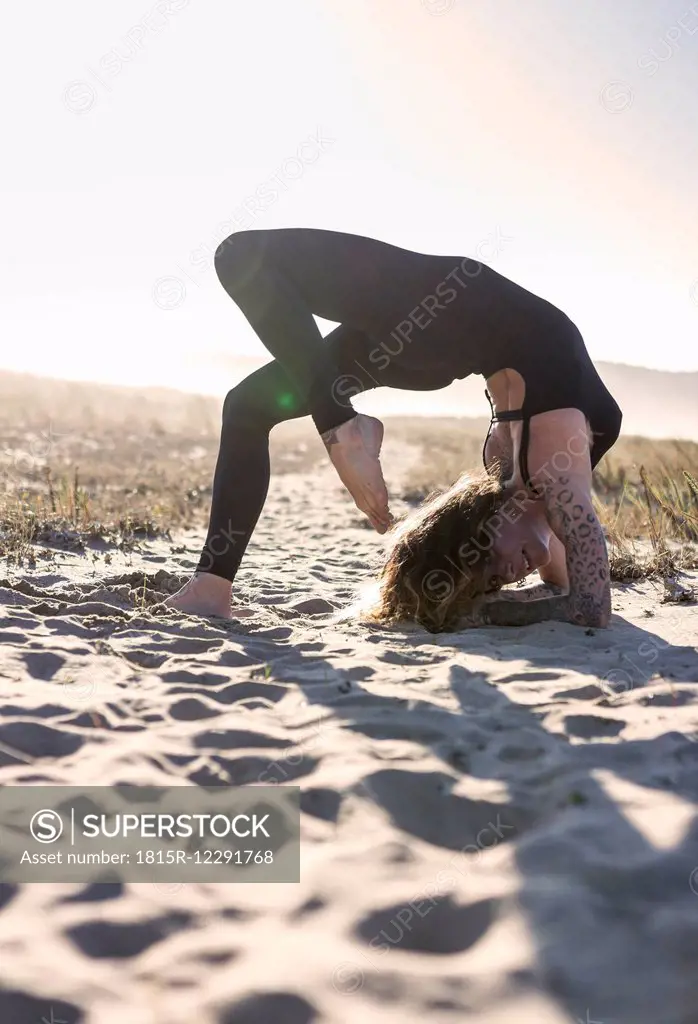 Spain, Asturias, Aviles, woman practicing yoga on the beach