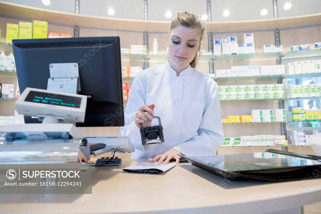 Young pharmacist in pharmacy stamping prescription
