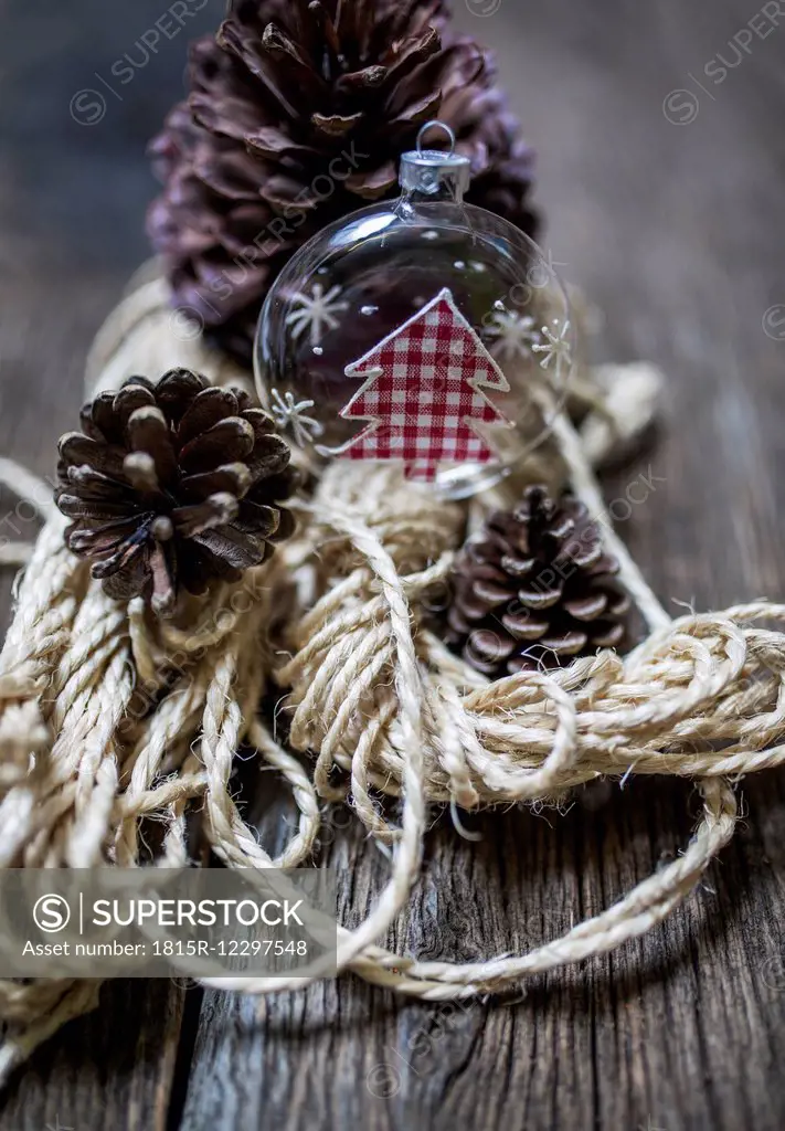 Rustic Christmas decoration with glass ornament, ribbon and cones on wood