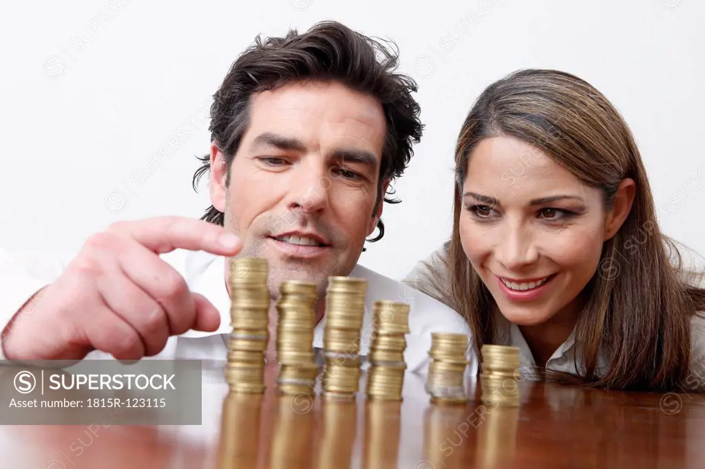 Germany, Bavaria, Munich, Businesswoman and man saving money, smiling