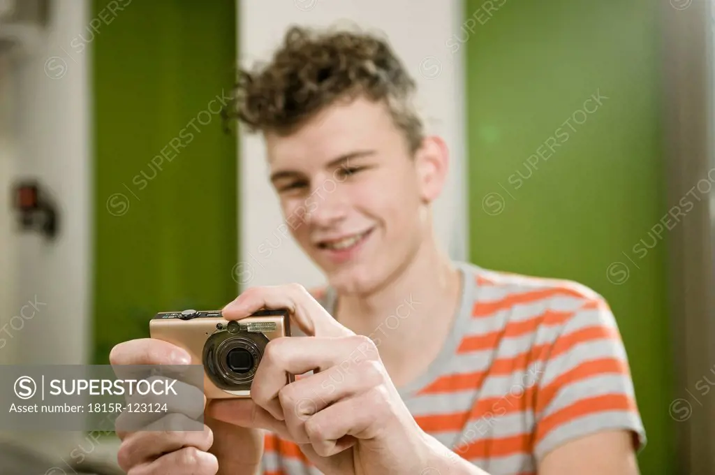 Germany, Bavaria, Munich, Young man using camera in cafe, smiling
