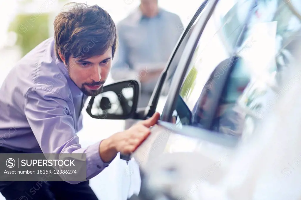 Car dealer examining car