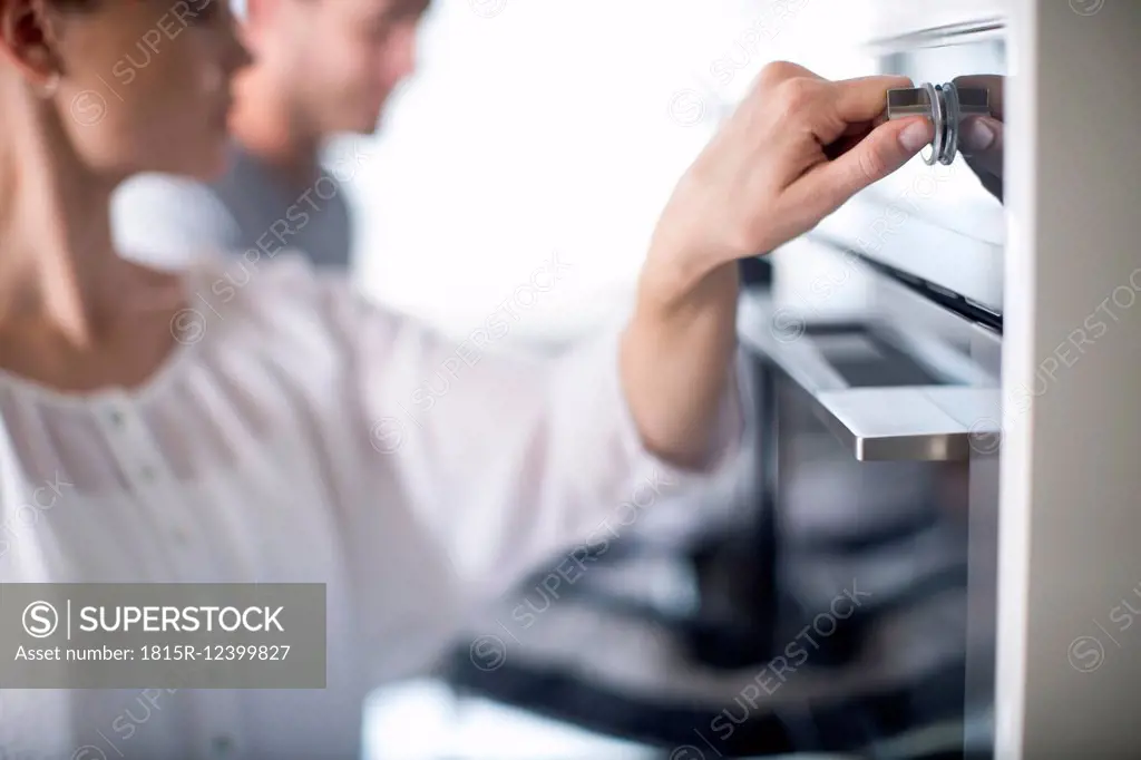 Woman adjusting temperature of oven