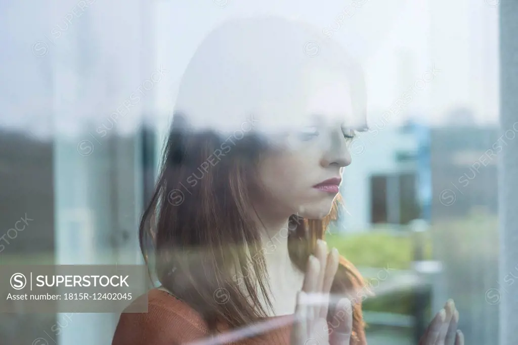 Serious young woman behind windowpane