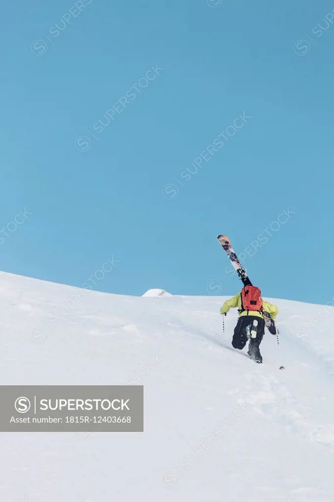 Austria, Tyrol, Arlberg, Young man ascending mountains with skis
