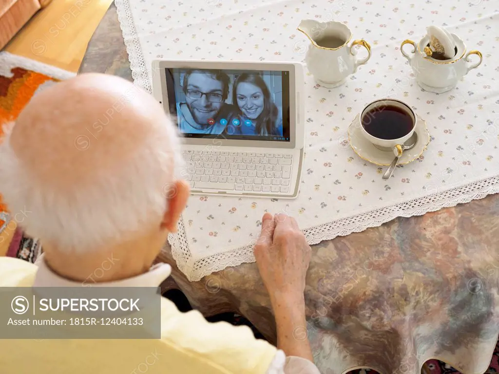 Grandfather videoconferencing with grandchildren via digital tablet