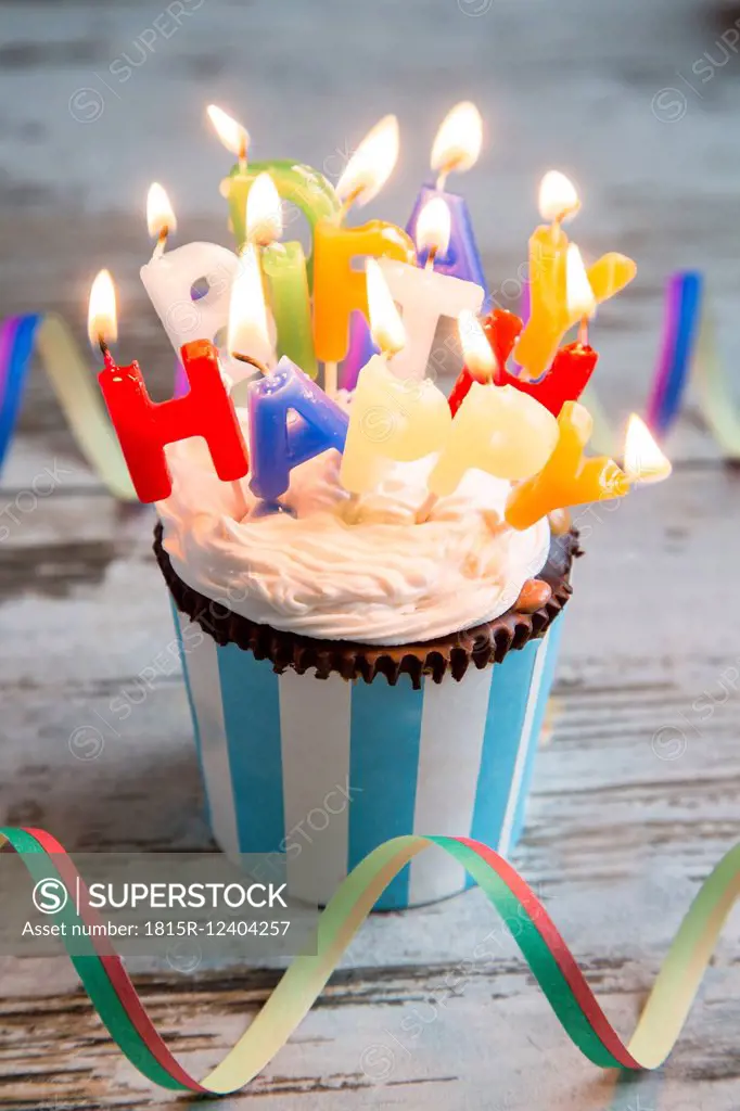 Birthday muffin with chocolate buttons and lighted candles