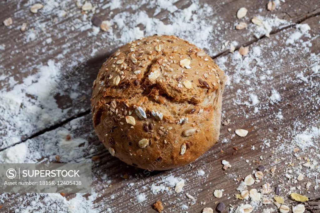 Wholemeal bread roll and flour on wood