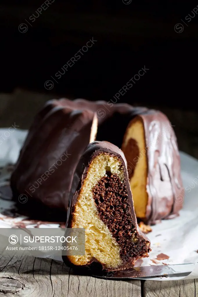 Marble cake, piece of chocolate cake and knife on greaseproof paper