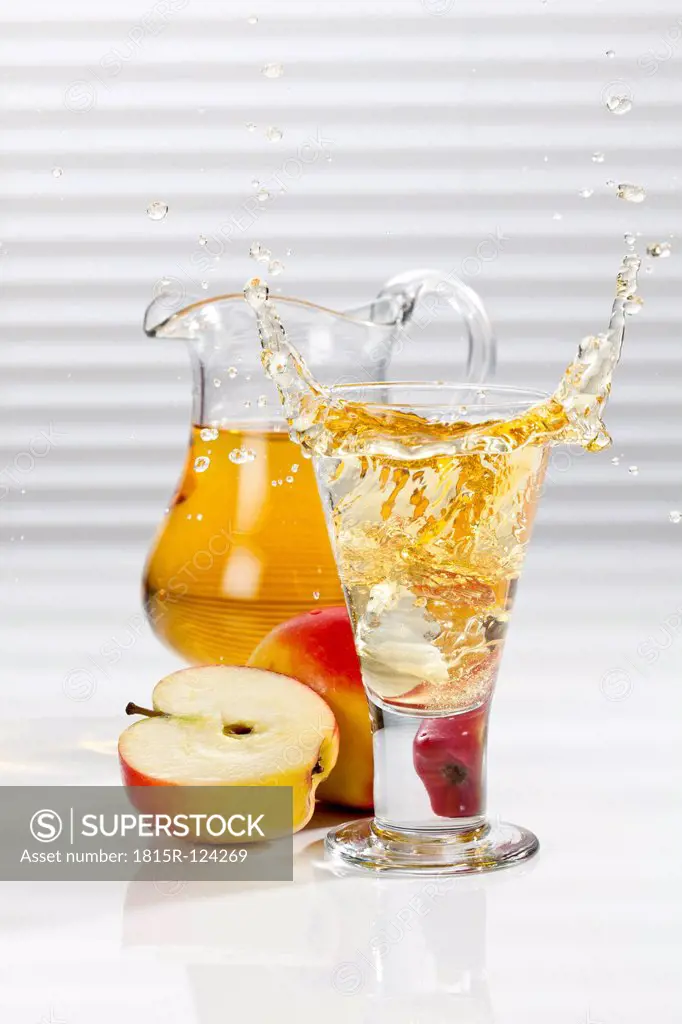 Glass of apple juice besides apples and pitcher