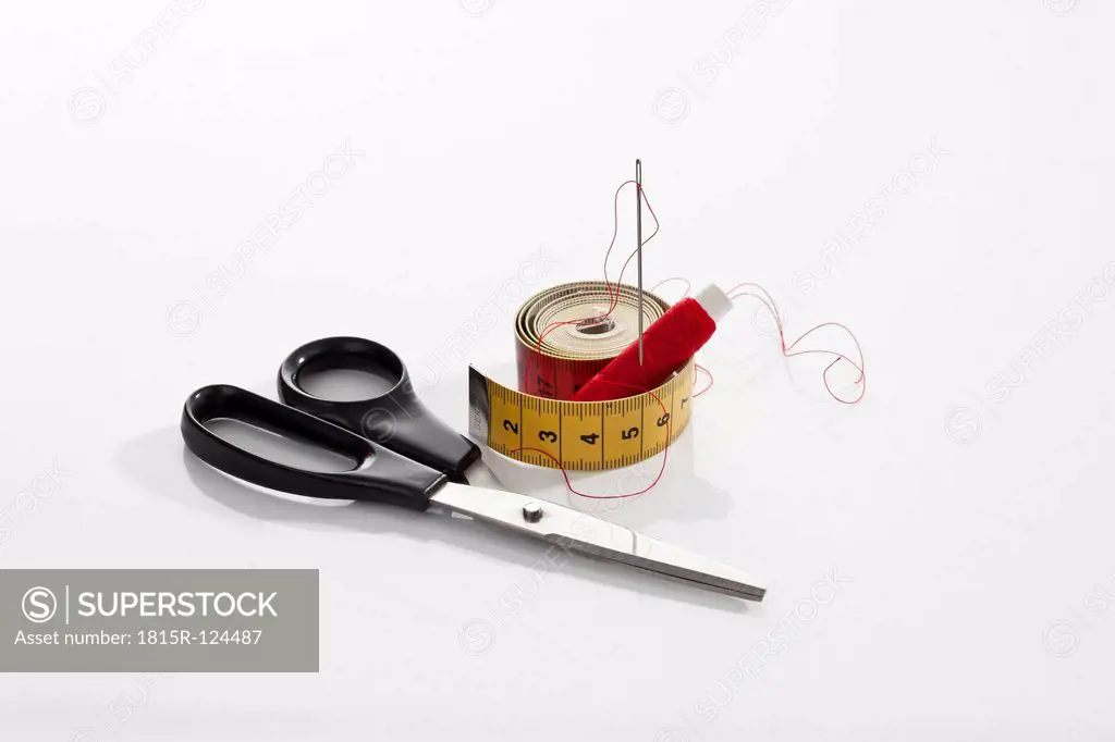 Scissors, needle, thread and measure tape on white background, close up